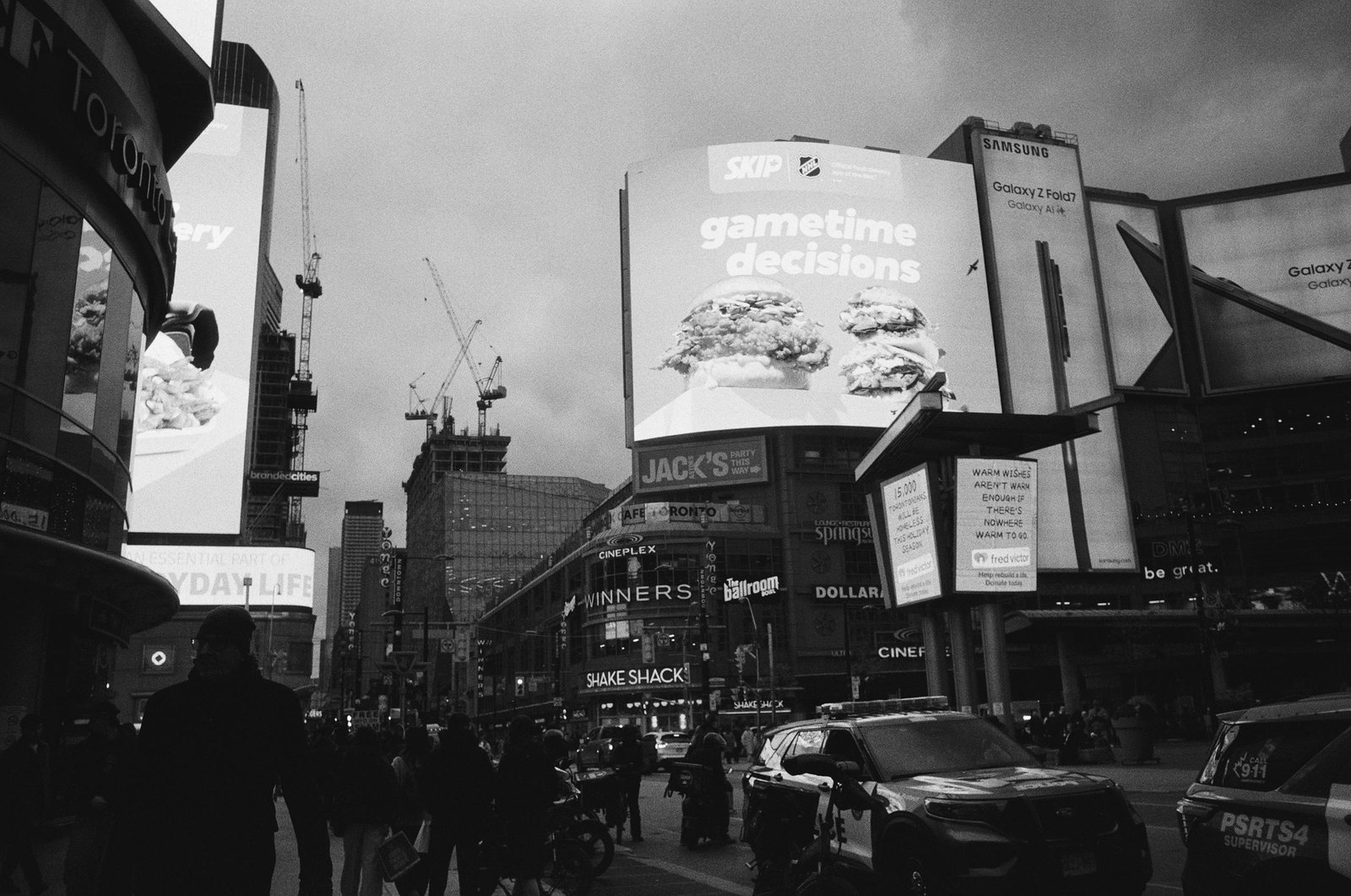 Toronto intersection beneath large billboards and a cloudy sky