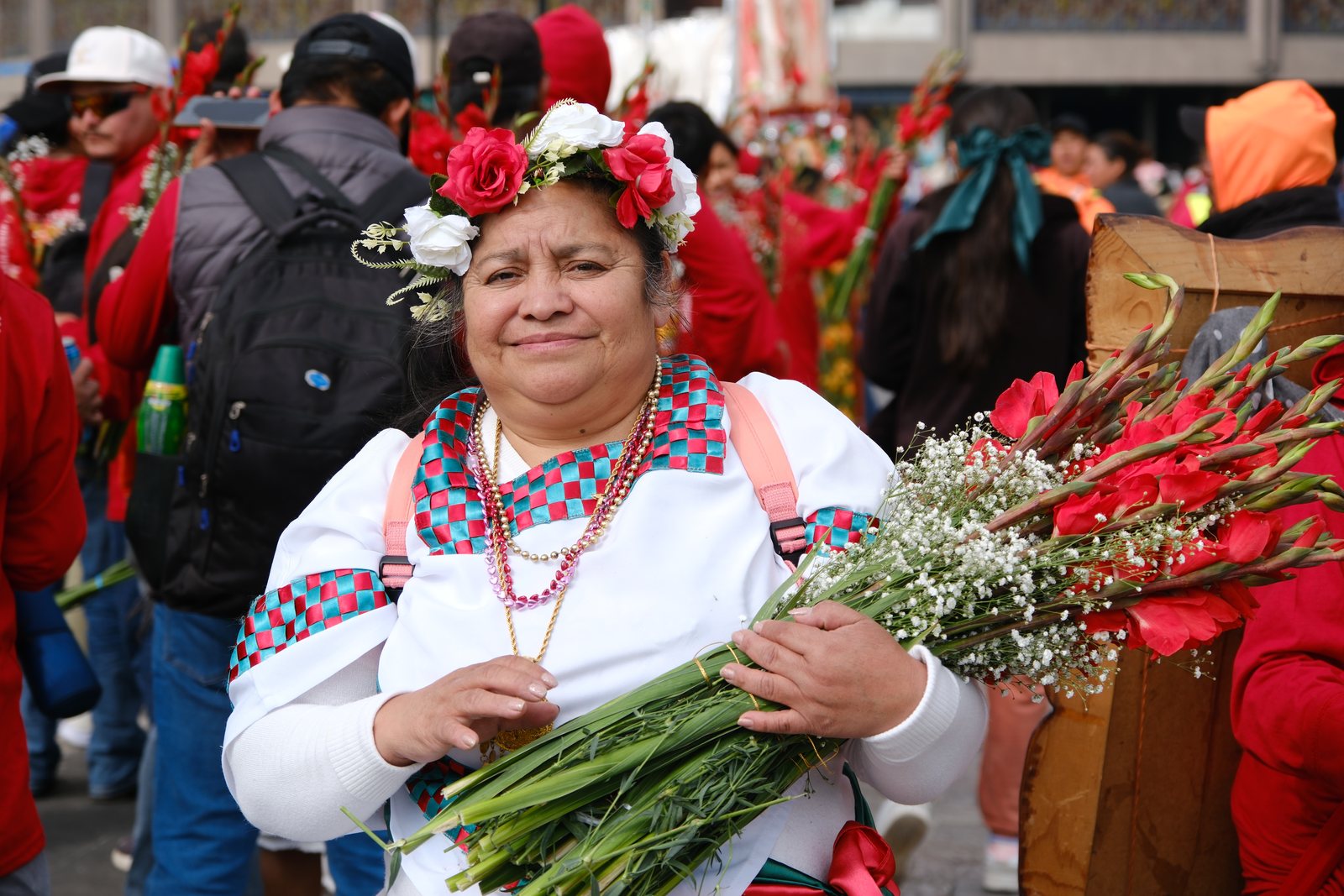 A woman wearing a flower crown and holding red roses